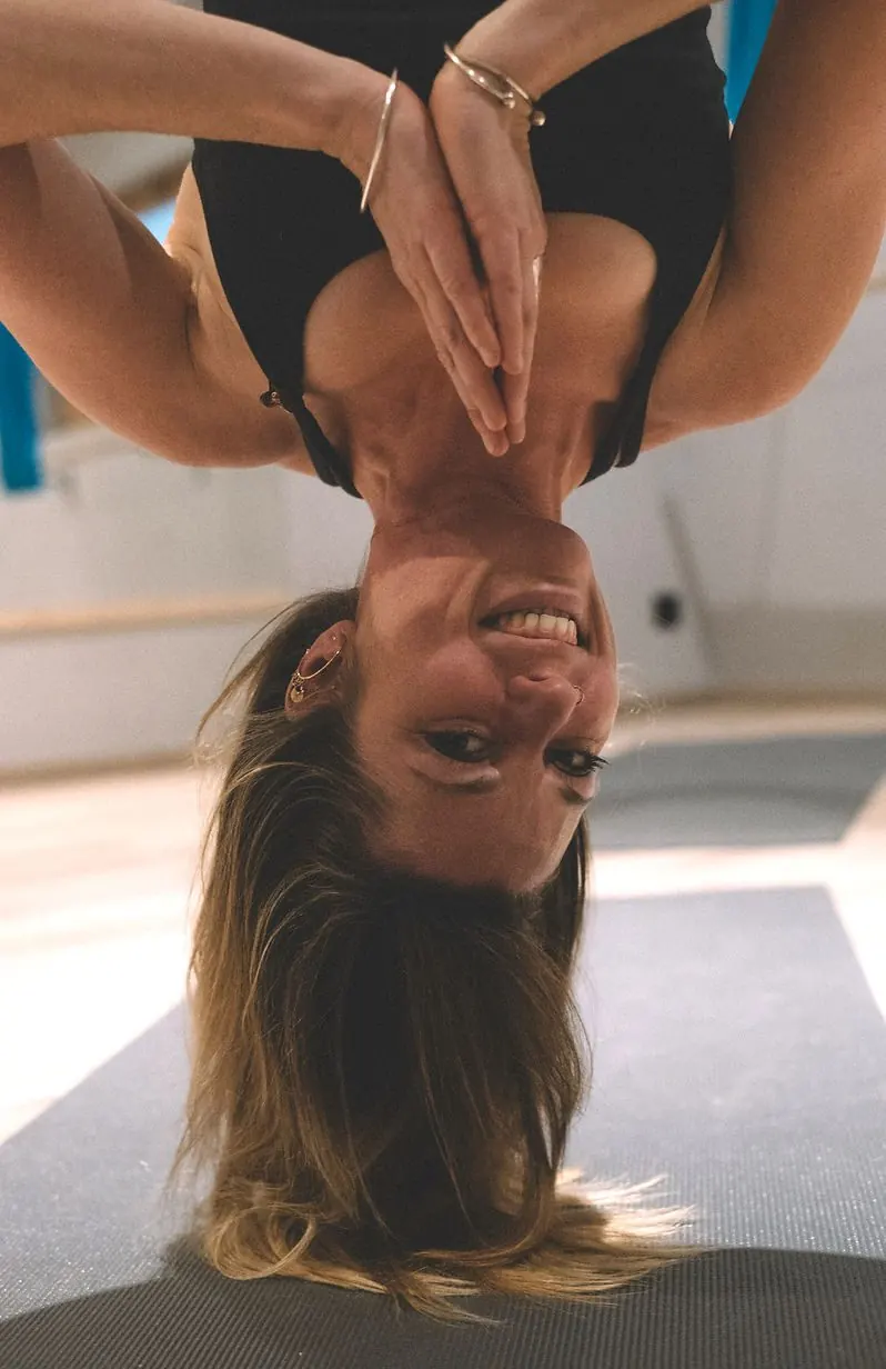 Gaëlle la tête en bas dans son hamac, mains jointes, tout sourire