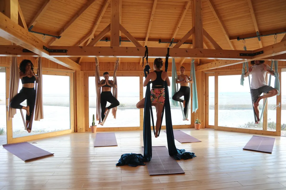 Participantes en posture dans leurs hamacs, sous le dôme en bois du lodge