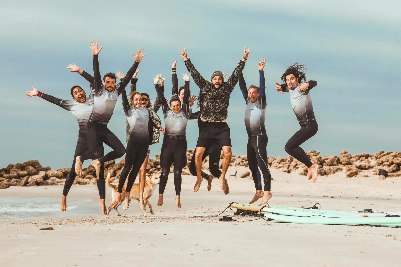 Le groupe de la retraite saute de joie sur la plage, en combinaison